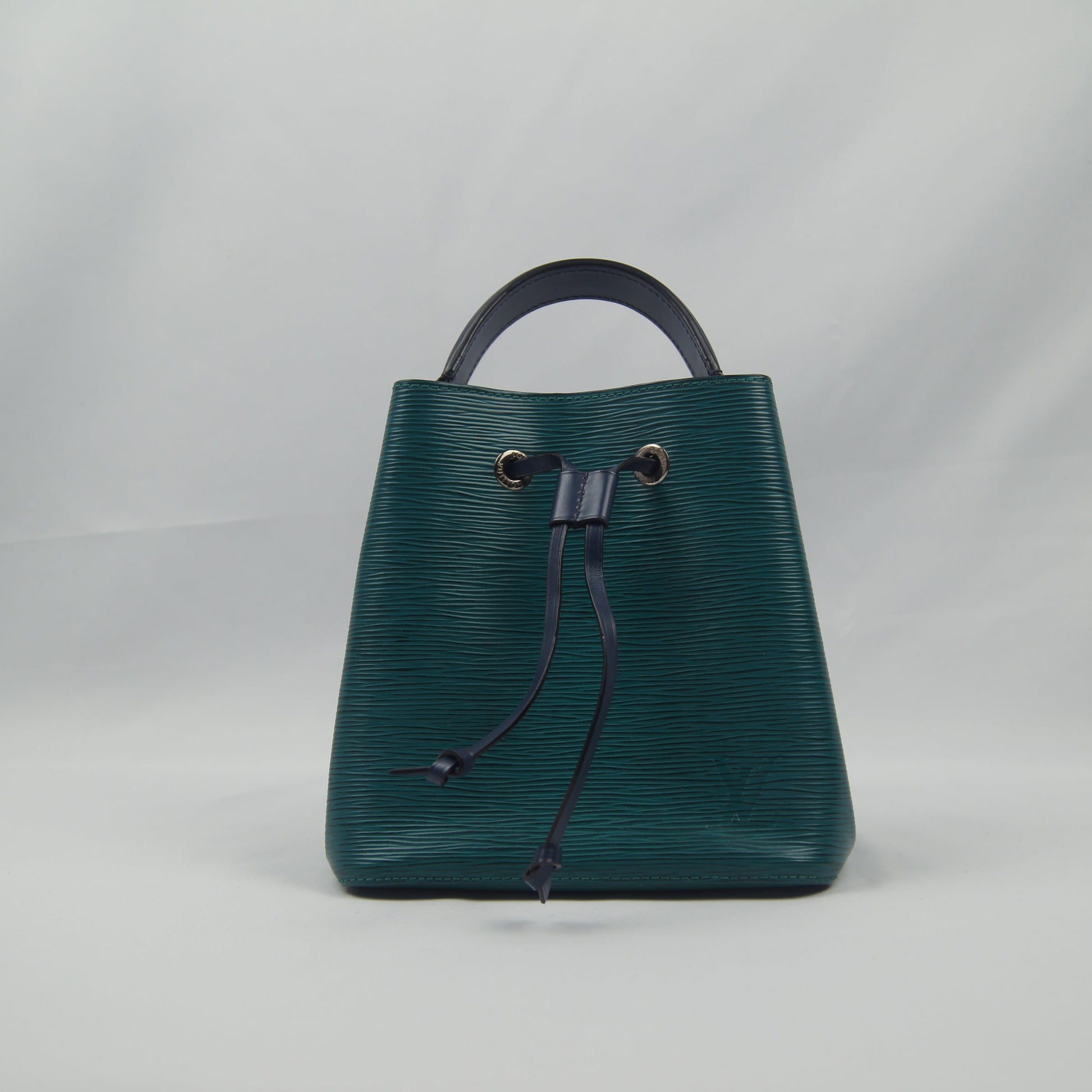Green handbag with a drawstring on a light gray background