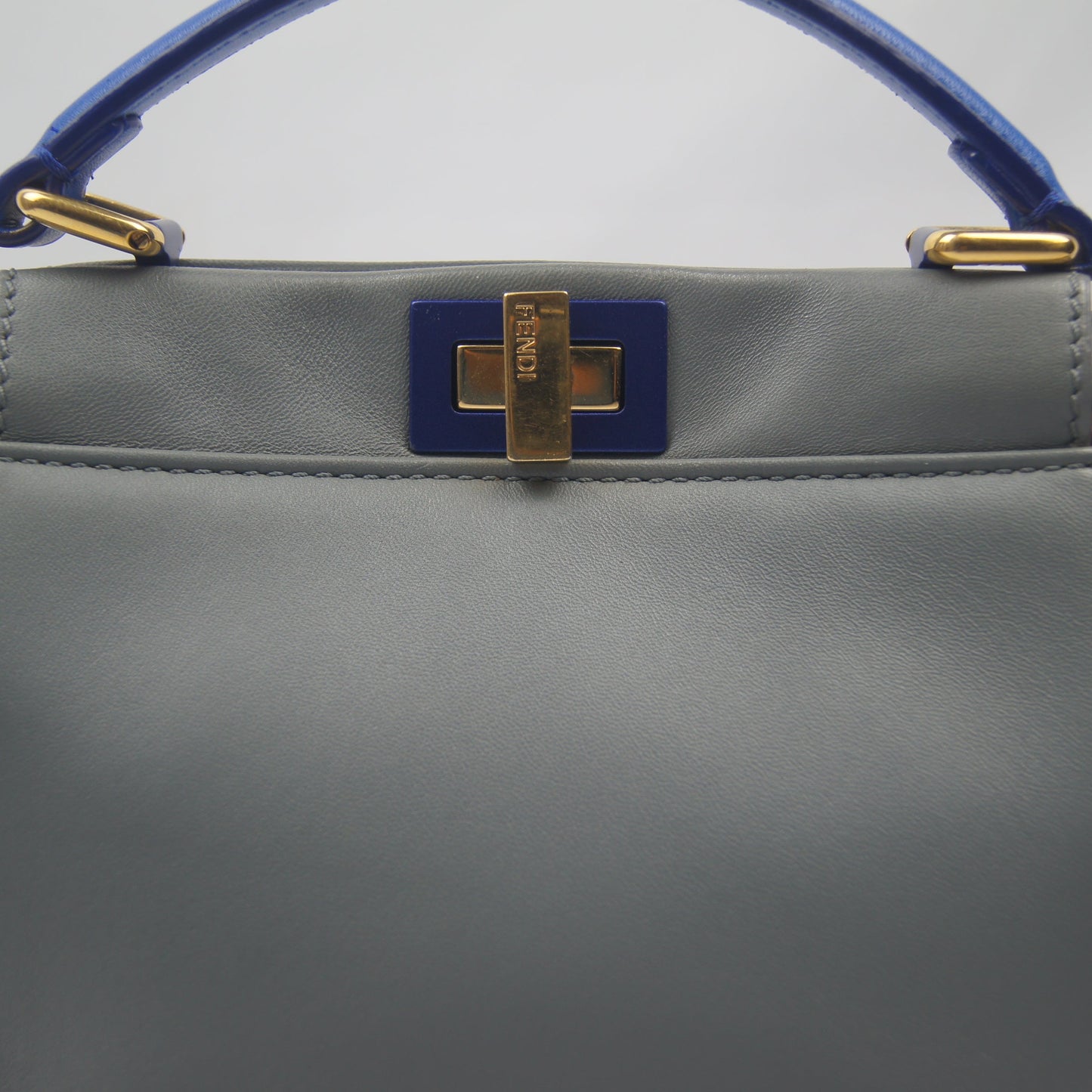 Gray handbag with blue handle and gold accents
