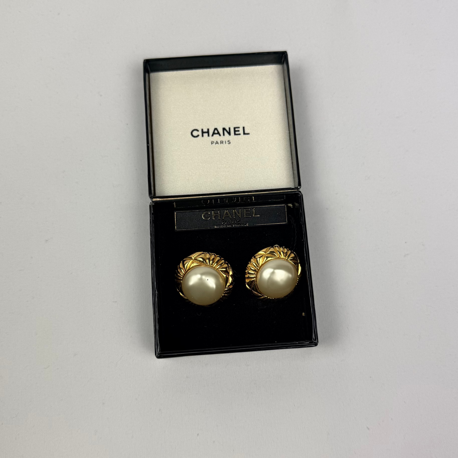 Chanel earrings in a black box on a light gray background